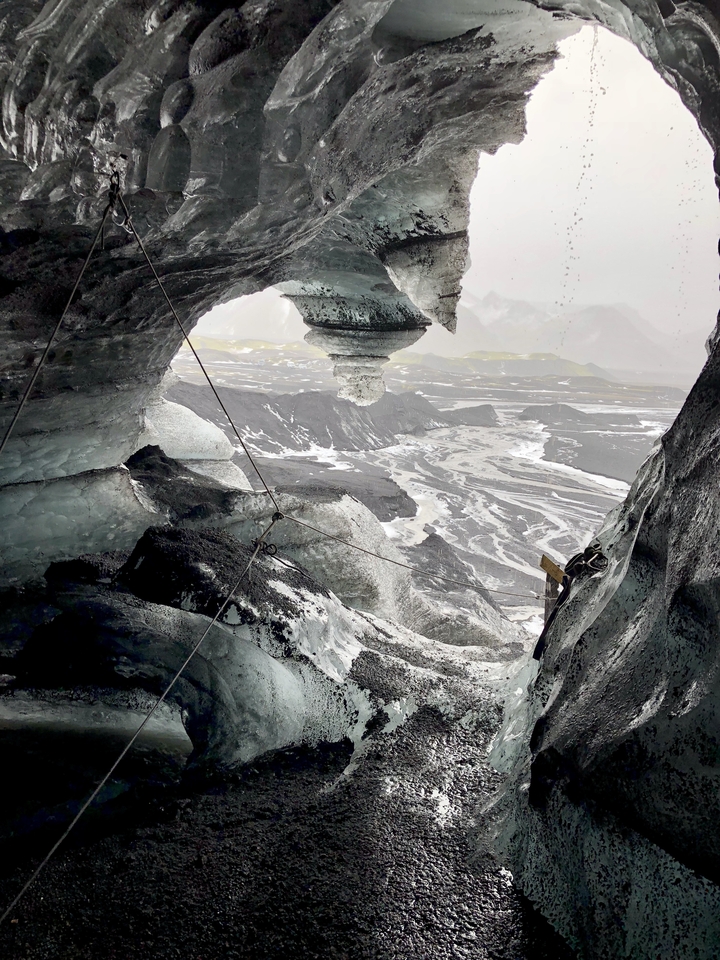 View from an icy cave overlooking a barren landscape.