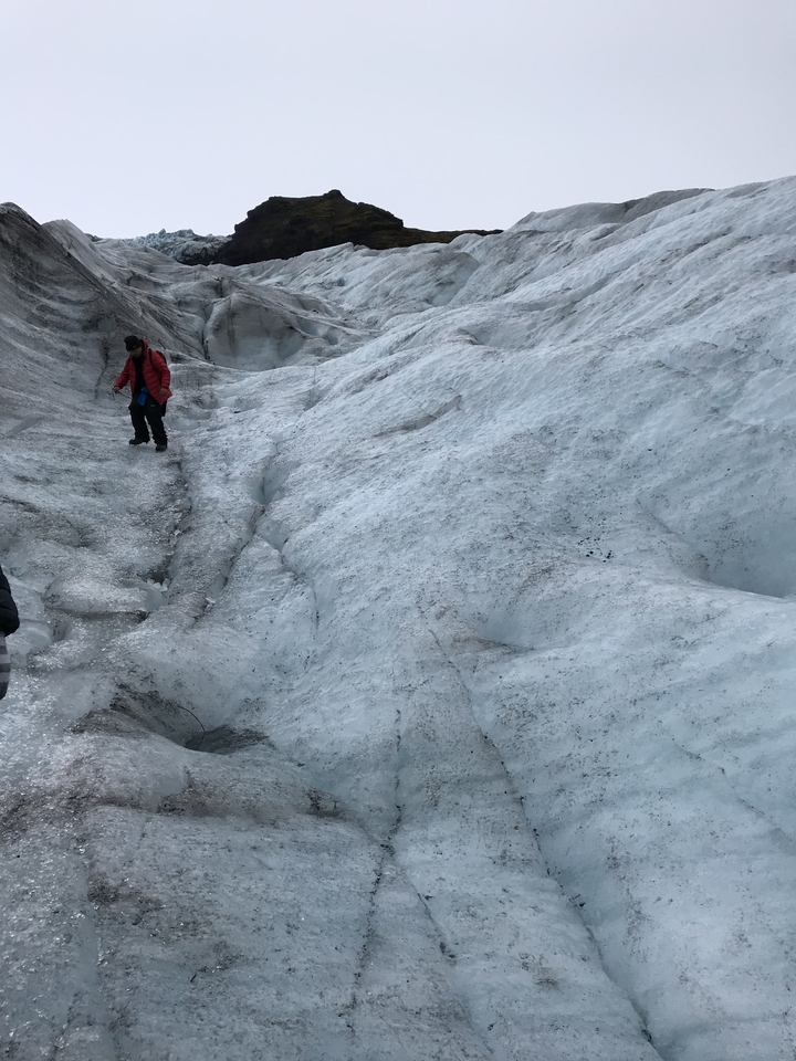 Person walking on a glacier with icy terrain.