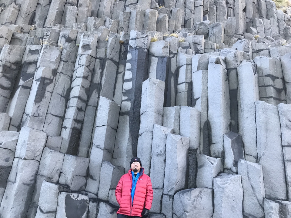 Person standing in front of columnar basalt formations.