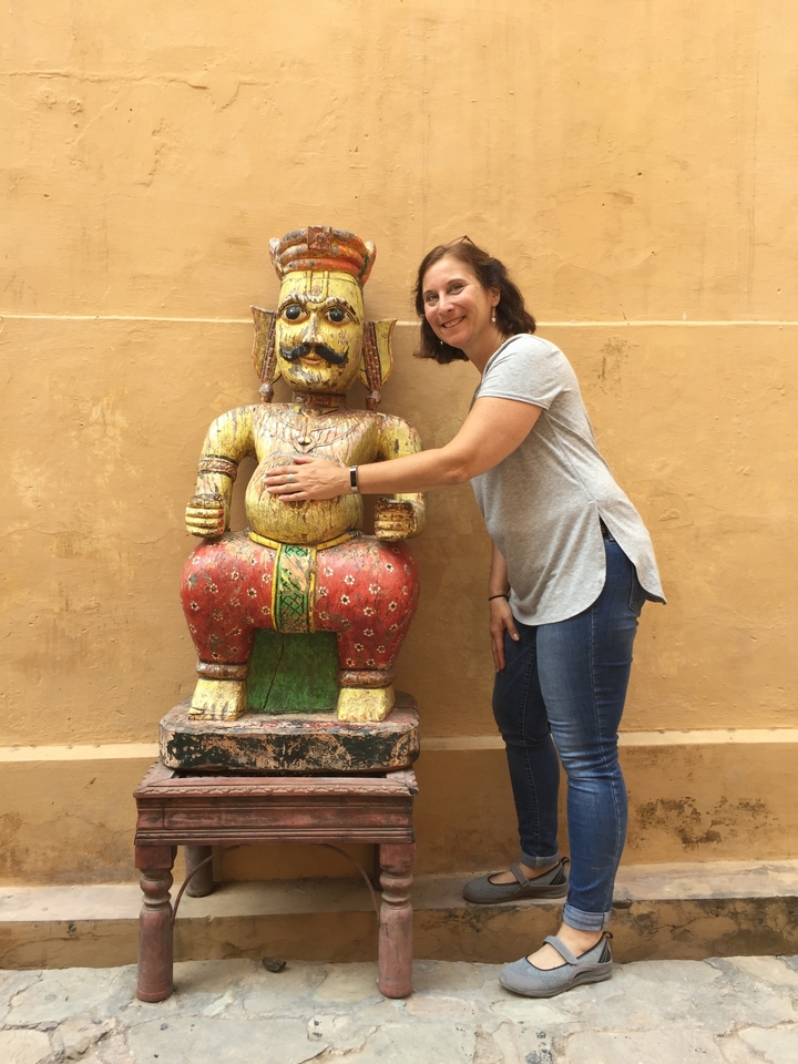 Femme posant à côté d'une statue colorée d'un homme avec une moustache.