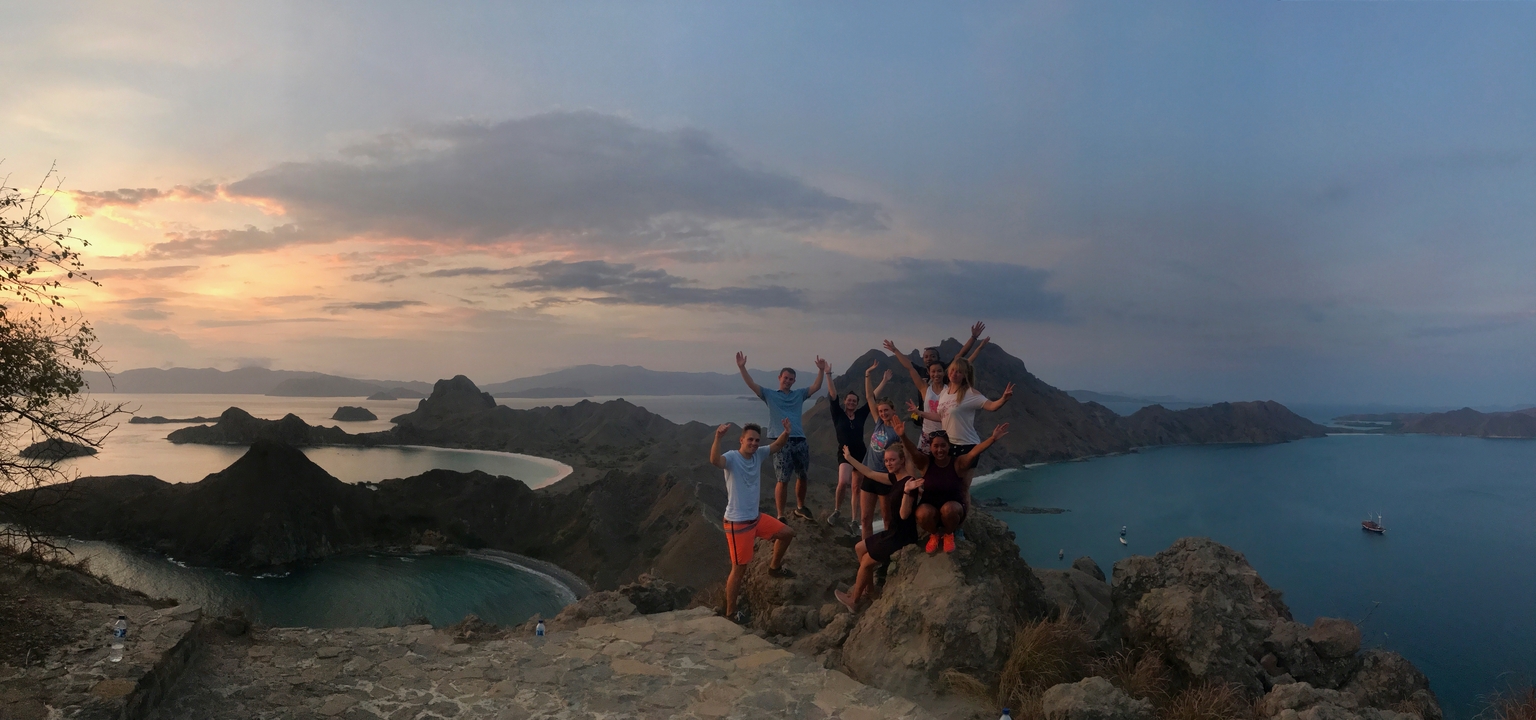Group of people celebrating on a cliff overlooking Padar Island.