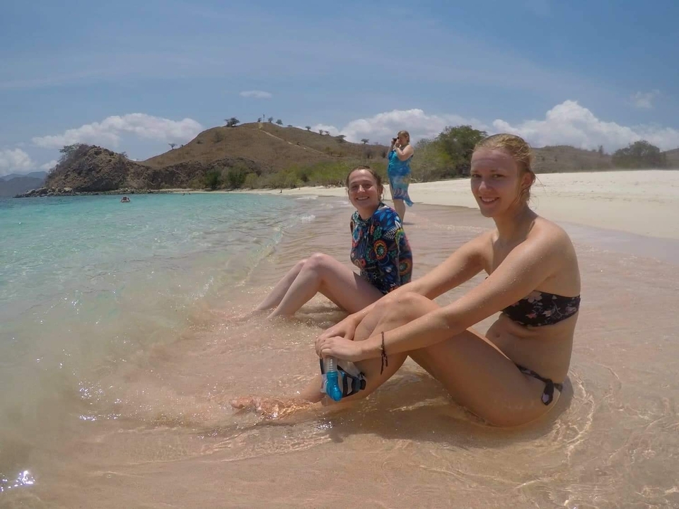 Two women sitting on the shore of a beautiful beach.