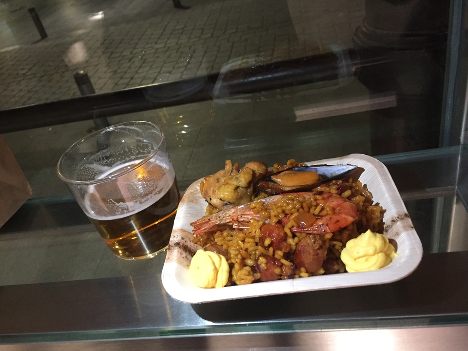 Une assiette de paella aux fruits de mer et un verre de bière.