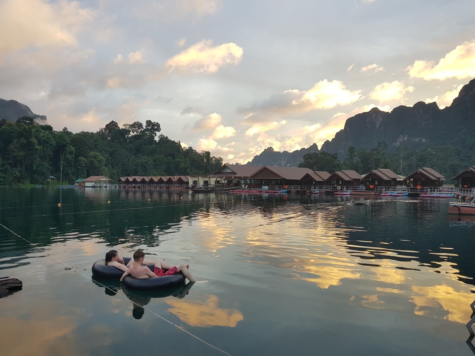 Two people relaxing on inner tubes on a lake at sunset.