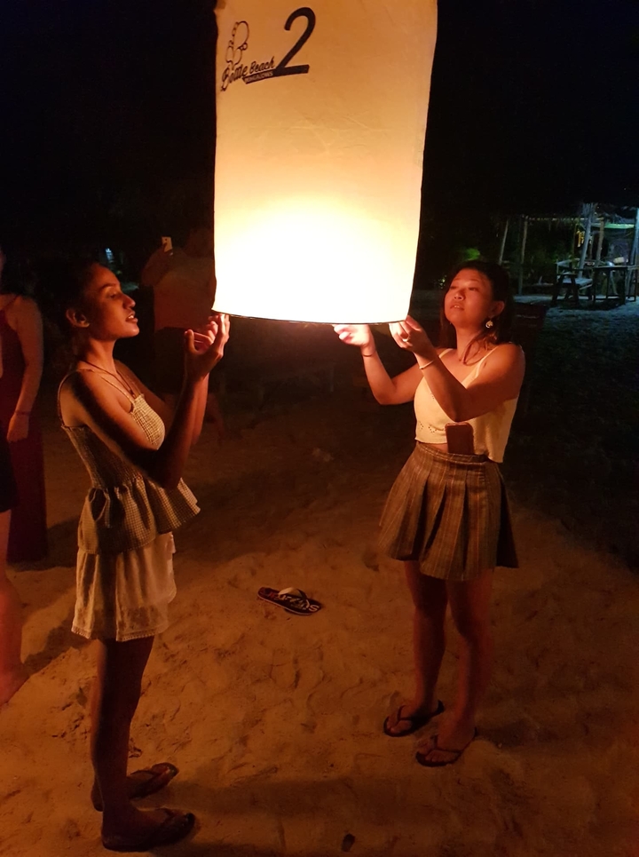 Two people launching a sky lantern at night.
