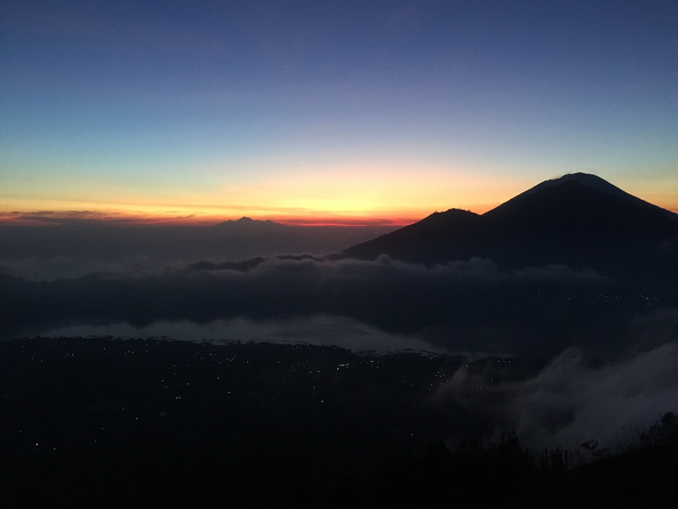 Sunset view with mountains and clouds over a valley.
