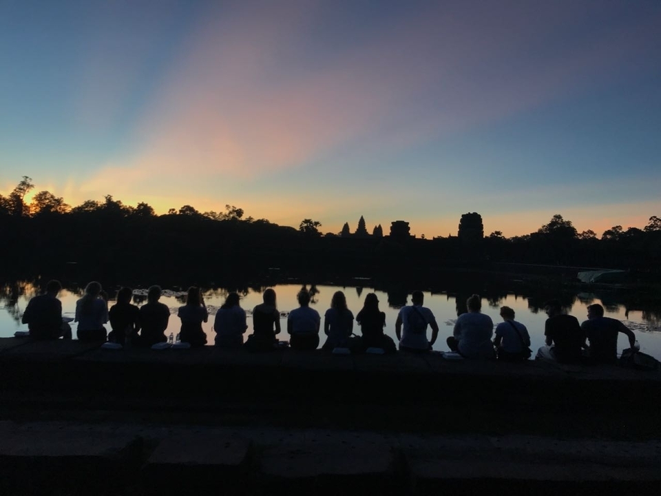 Silhouette of people sitting by water during sunset.