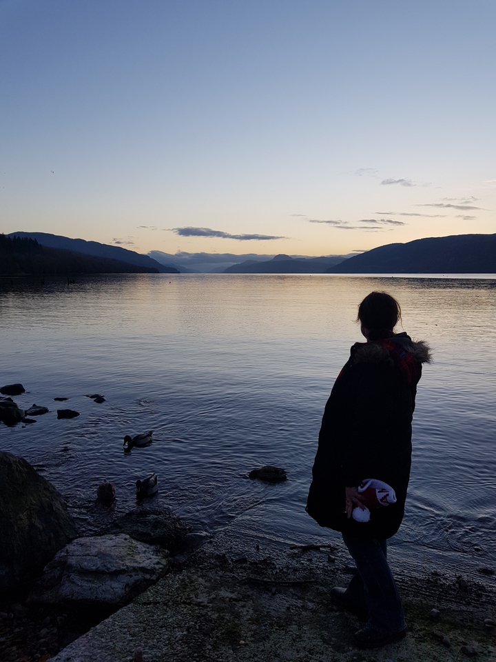 Woman with a lake and mountains in the background.