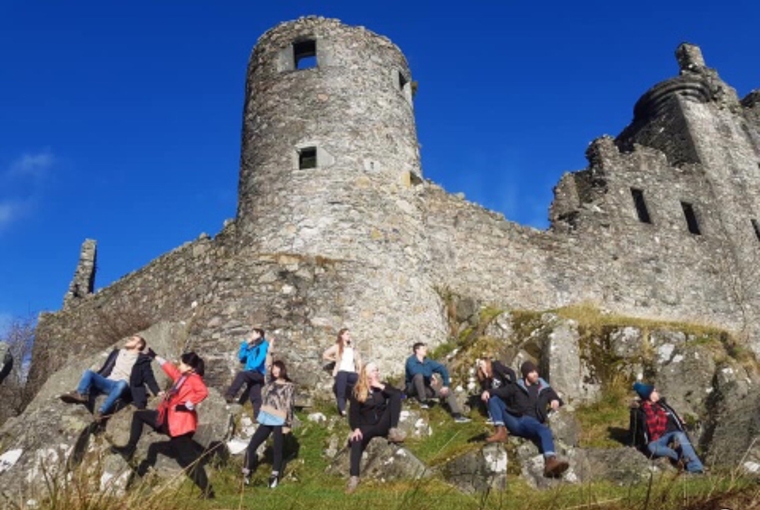 Group of people posing in front of a stone castle.