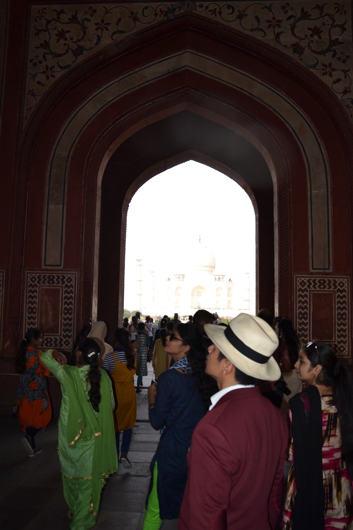 People walking through an arch with the Taj Mahal in the background.