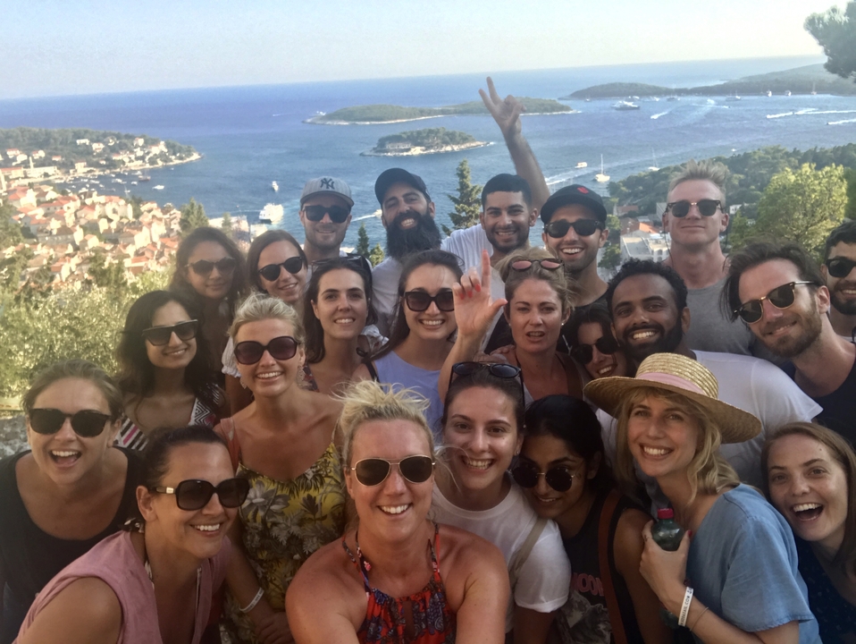 A large group of people posing with a sea view in Hvar Island.