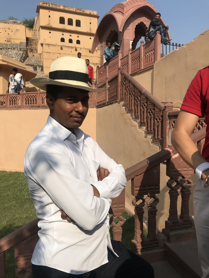 Man standing next to another person in an outdoor setting with historic architecture.