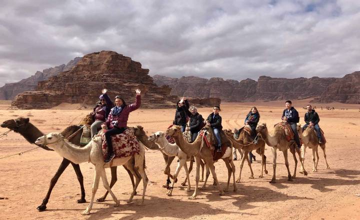 Group riding camels in a desert landscape.