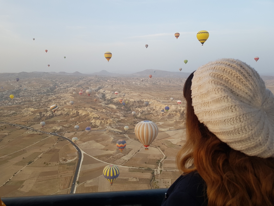 Person observing hot air balloons over Cappadocia.