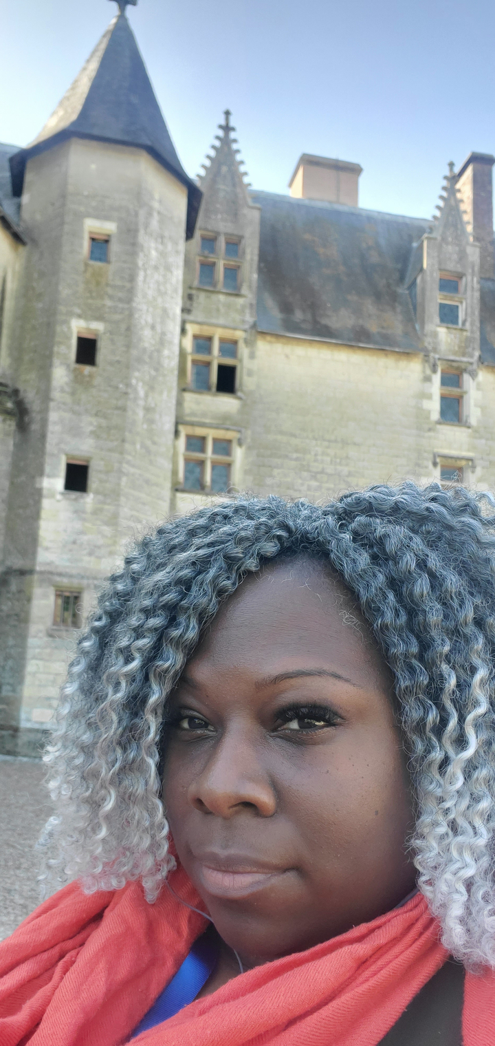 Gros plan sur les cheveux d'une personne avec un château de pierre en arrière-plan.