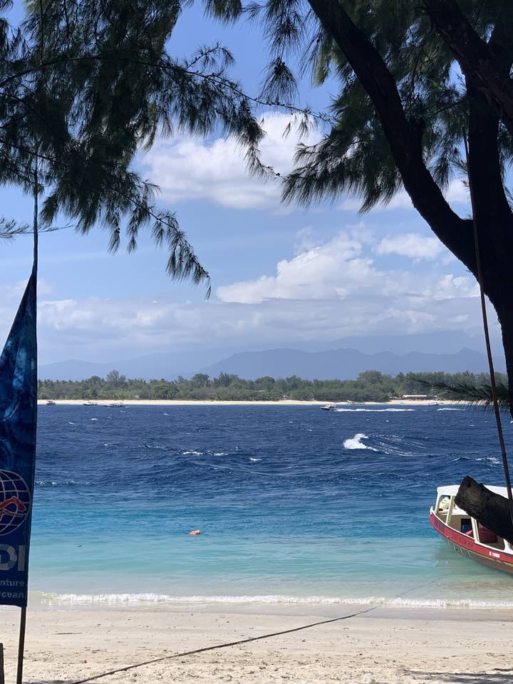 Sandy beach and turquoise sea lined with trees.