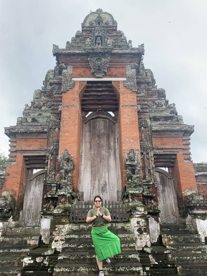 Person in front of traditional Balinese temple gate.
