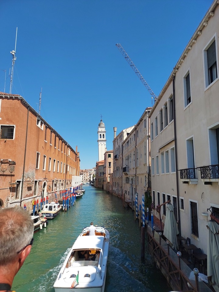 Narrow canal with historic buildings and a bell tower.