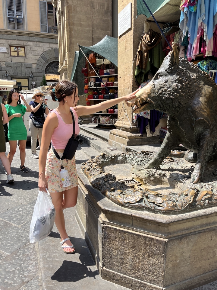 Woman interacting with a bronze boar statue