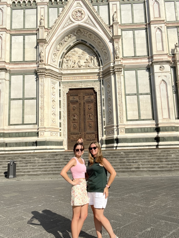 Two women posing in front of a large church door