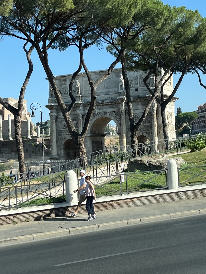 Historic arch with trees and people nearby