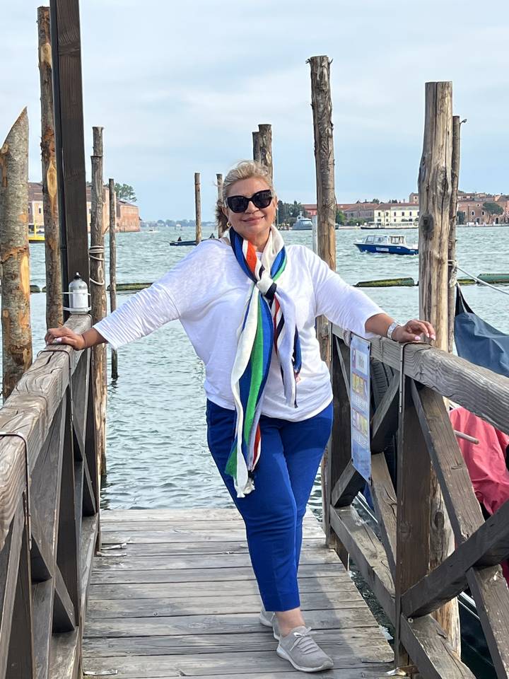 Woman posing on a wooden dock by the water.