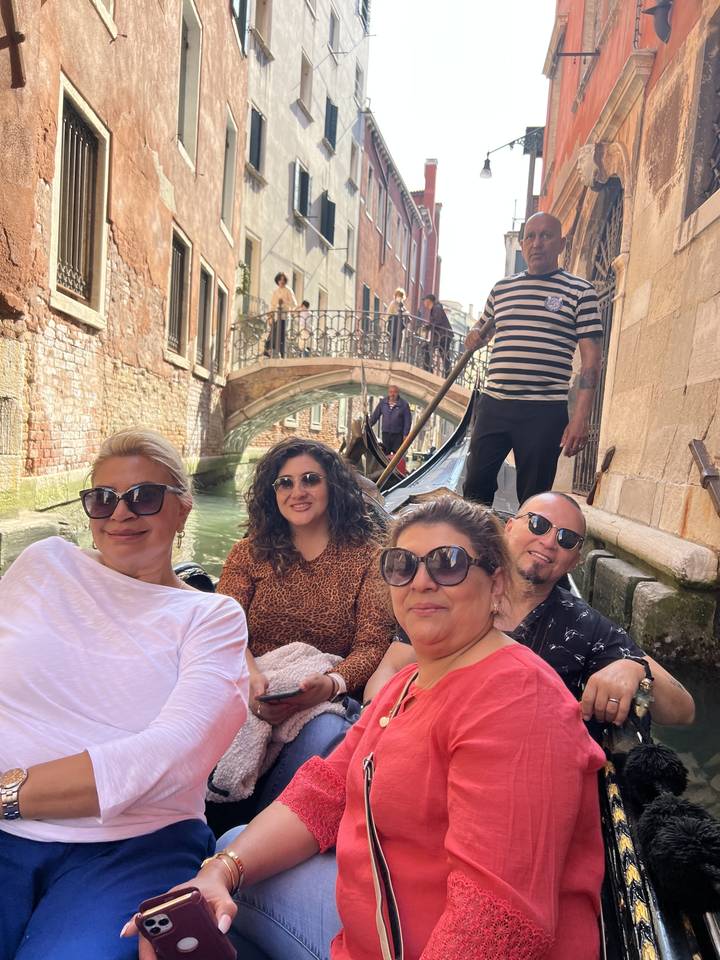 Group of people in a gondola on a Venetian canal.