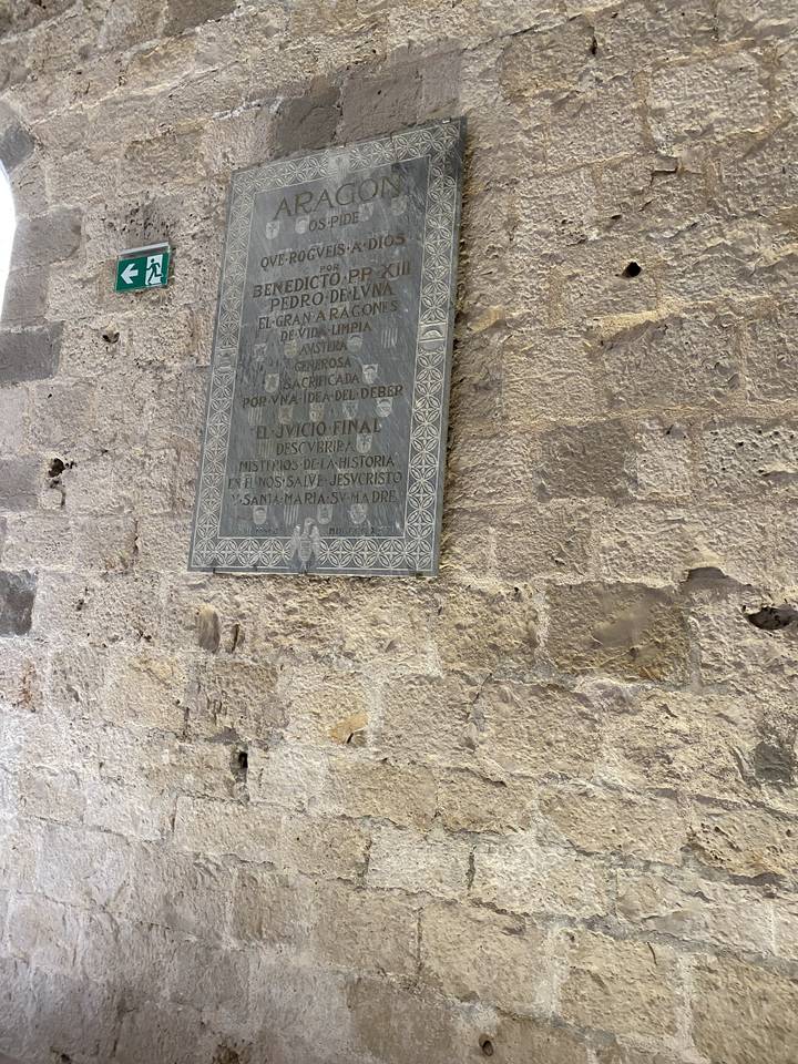 An upside-down plaque on a stone wall.