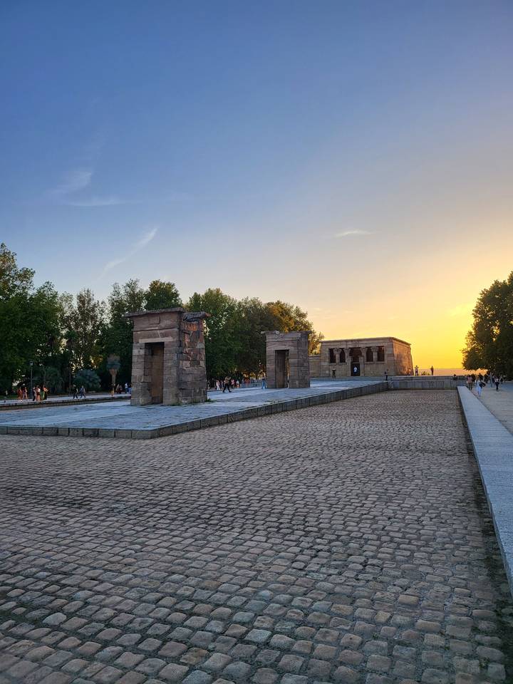 Sunset over stone structures in a park setting.
