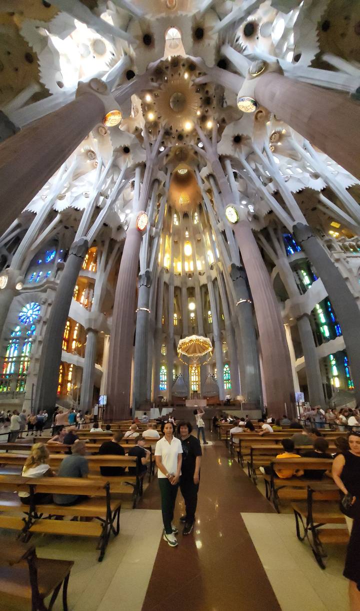 Interior of a large cathedral with stained glass and people.