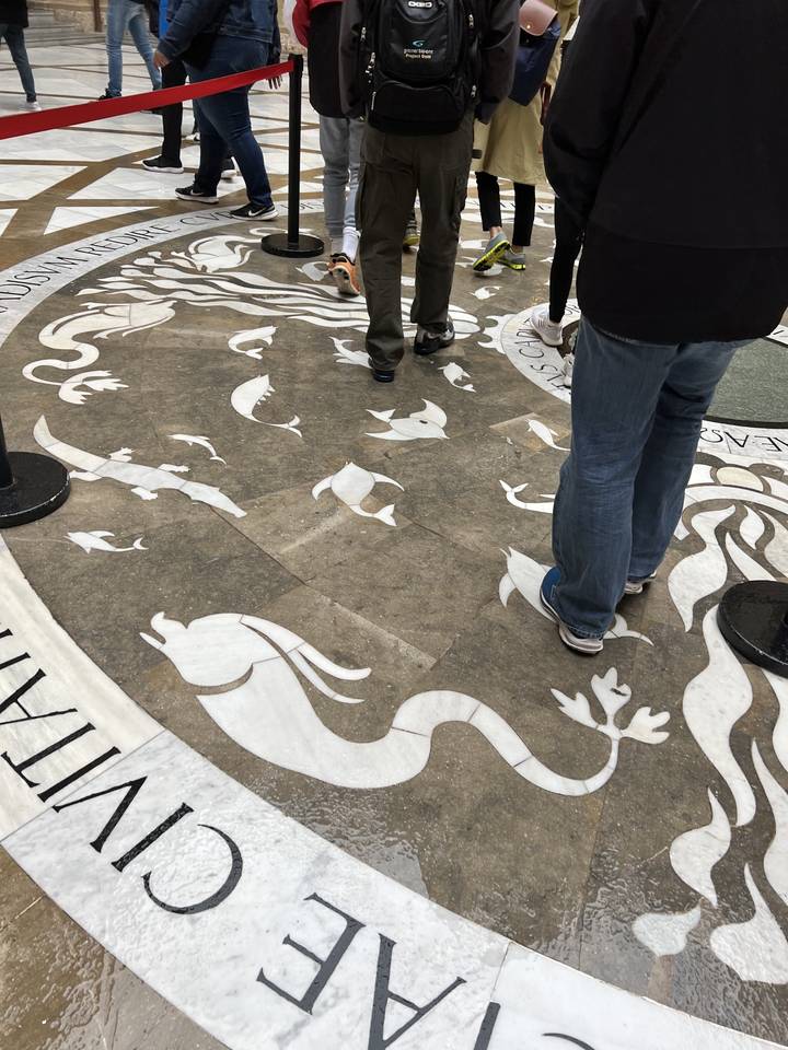 Mosaïque de sol avec des personnes debout autour.