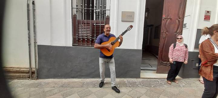Homme jouant de la guitare dans la rue avec des spectateurs.