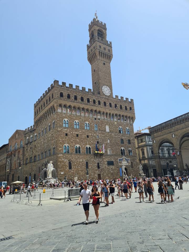 People in front of a large brick building with a clock tower