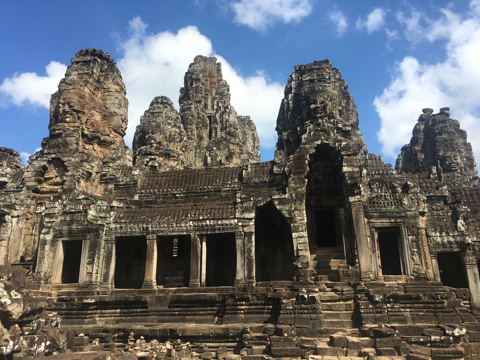 Majestueuze stenen tempel met gebeeldhouwde gezichten op torens.
