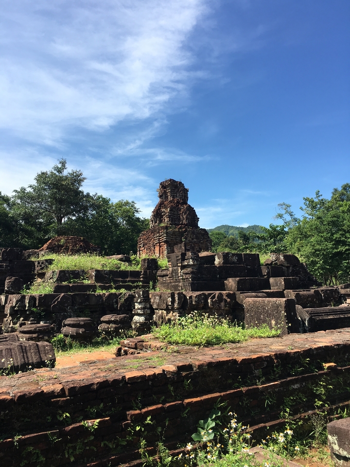 Ruines d'un ancien temple hindou avec des arbres et un ciel dégagé.