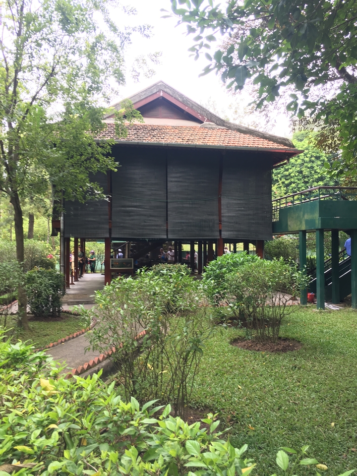 Maison traditionnelle surélevée sur pilotis au milieu de la verdure.
