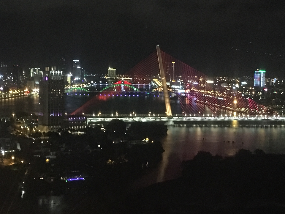 Pont et bâtiments au bord de la rivière illuminés la nuit.