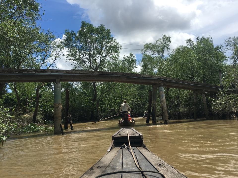 Bateau naviguant sous un simple pont en bois.