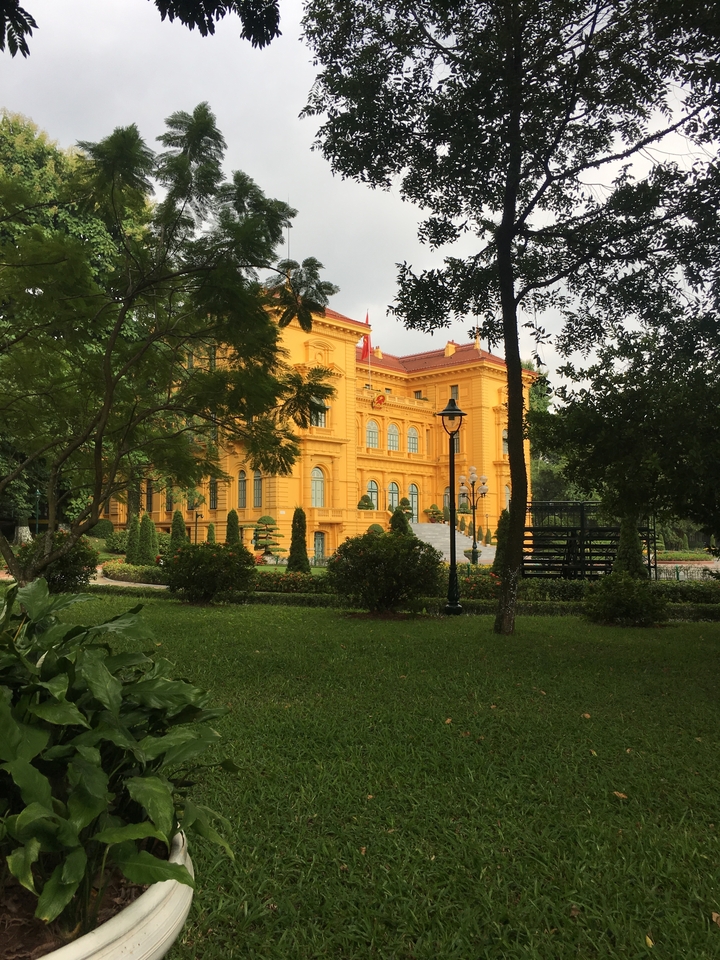 Yellow colonial-style building in a manicured garden.