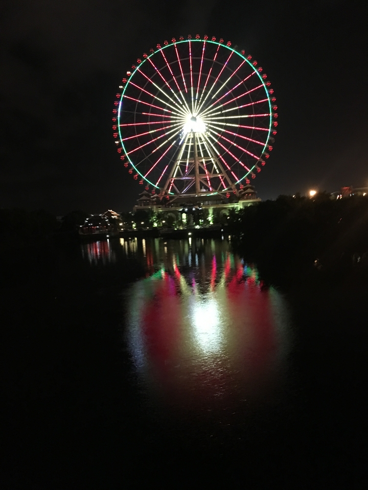 Grande roue illuminée de lumières colorées la nuit.