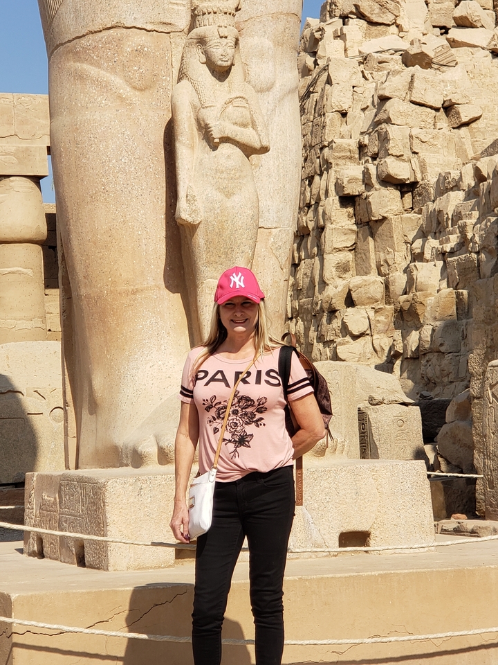 A woman posing in front of a statue.