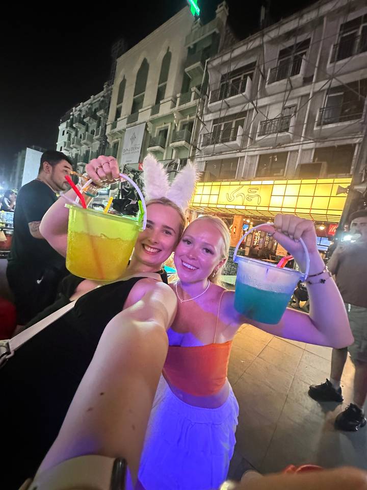 Two people holding colorful drinks on a street.