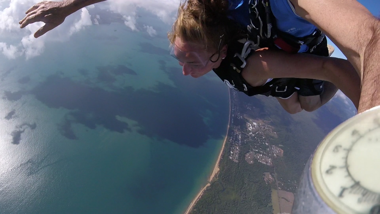 Skydiver above a coastal landscape.