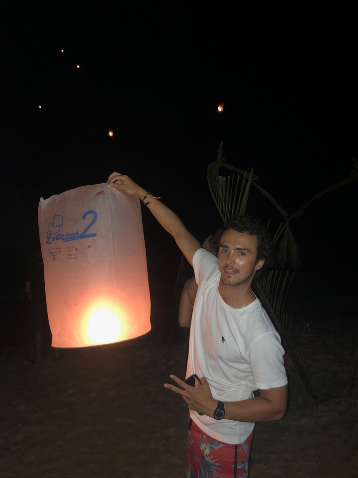 Person launching a lantern at night on a beach.