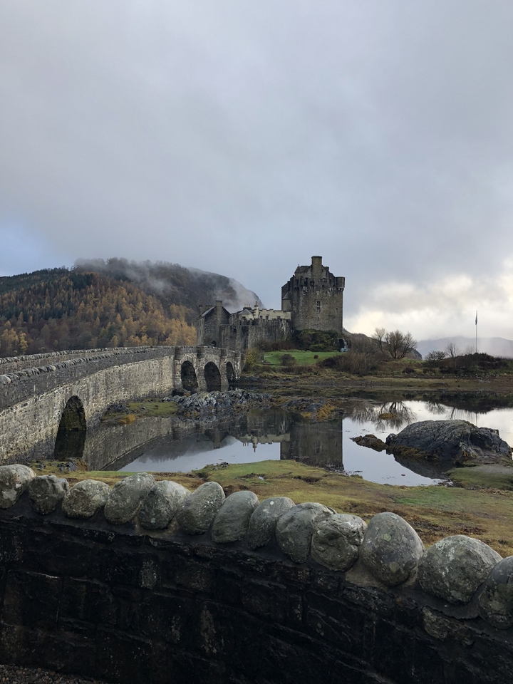 Scenic view of Eilean Donan Castle besides a stone bridge.