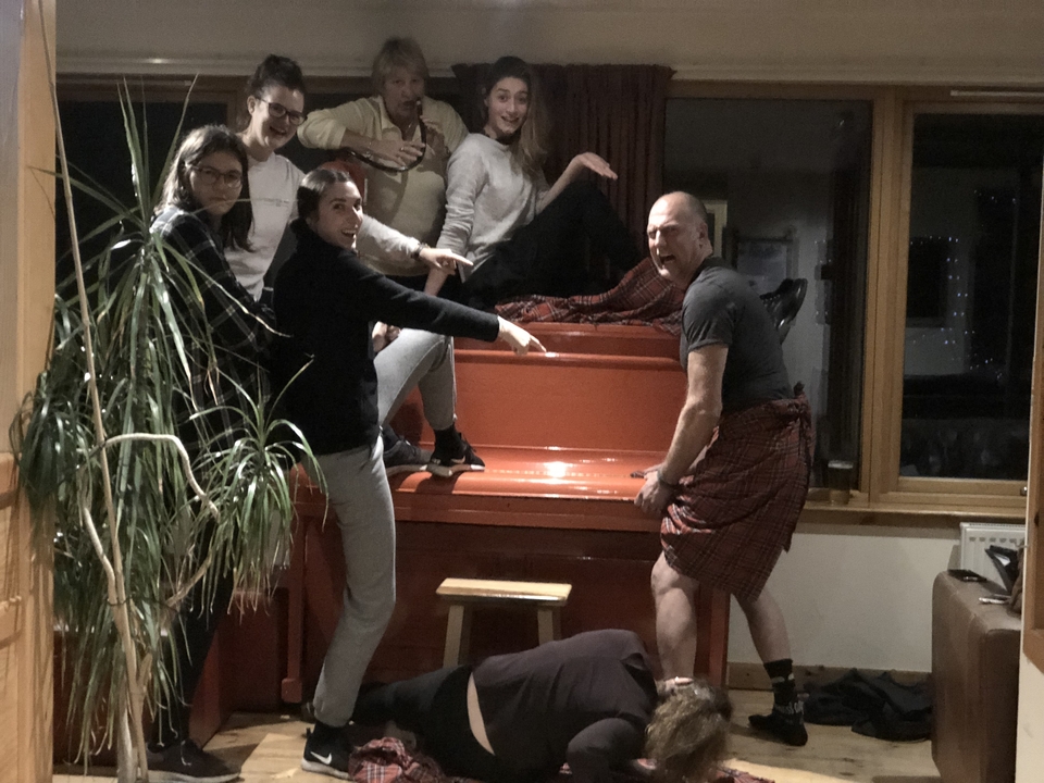 Groupe posant de manière ludique autour d'un piano à l'intérieur.