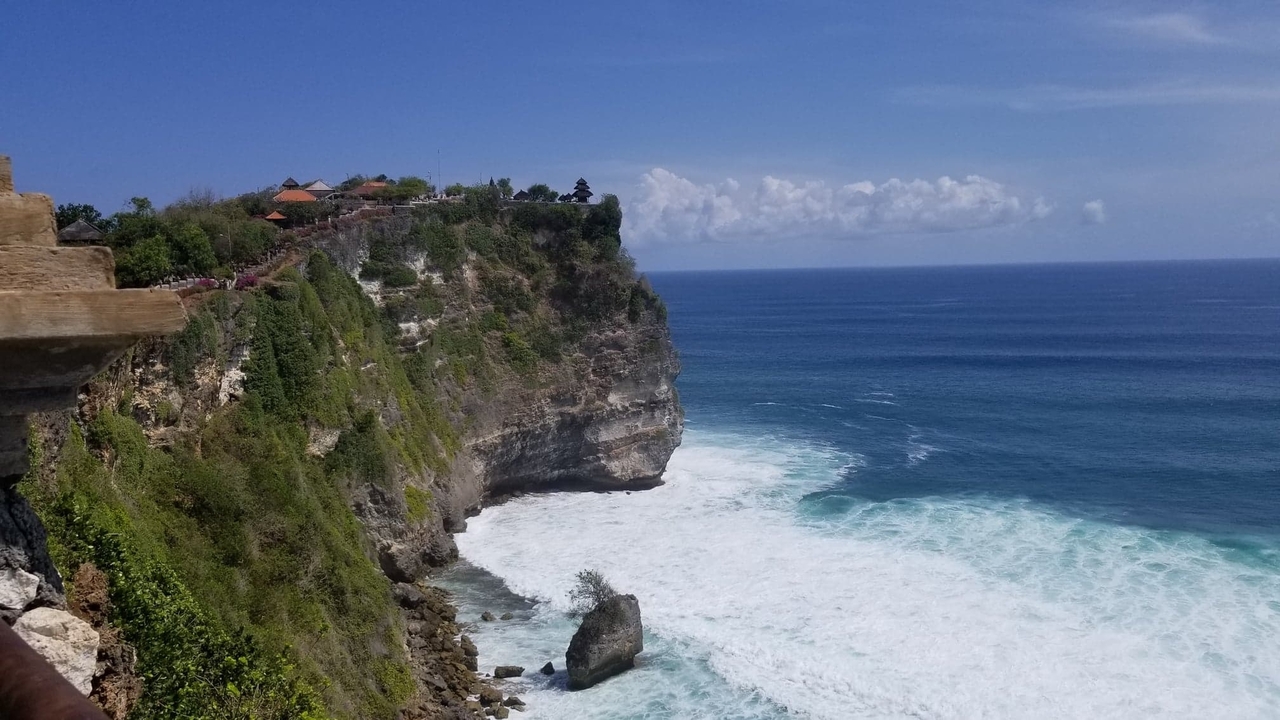 Cliffside view overlooking the ocean with waves crashing against rocks.