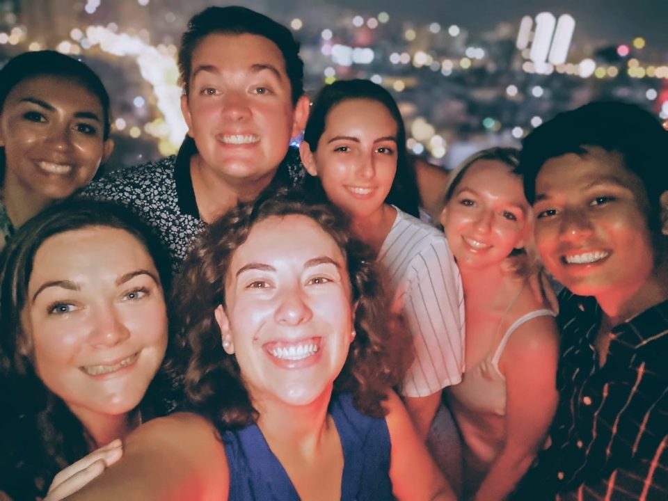 A group selfie taken at night with city lights in the background.