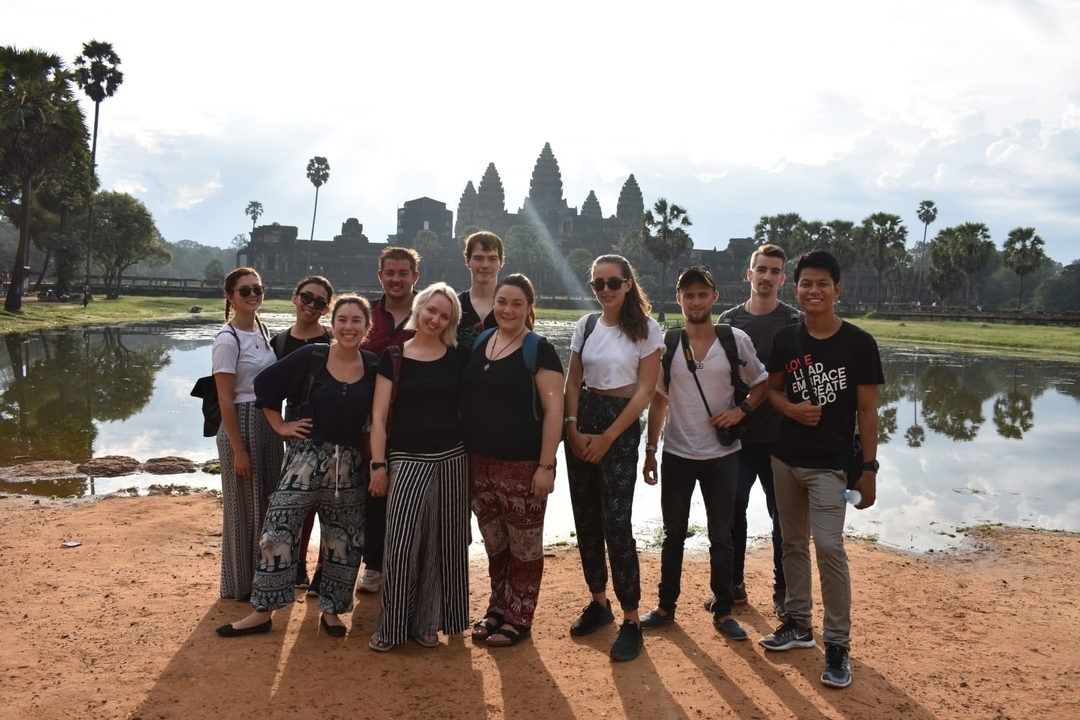 A group of people posing in front of the iconic Angkor Wat temple.