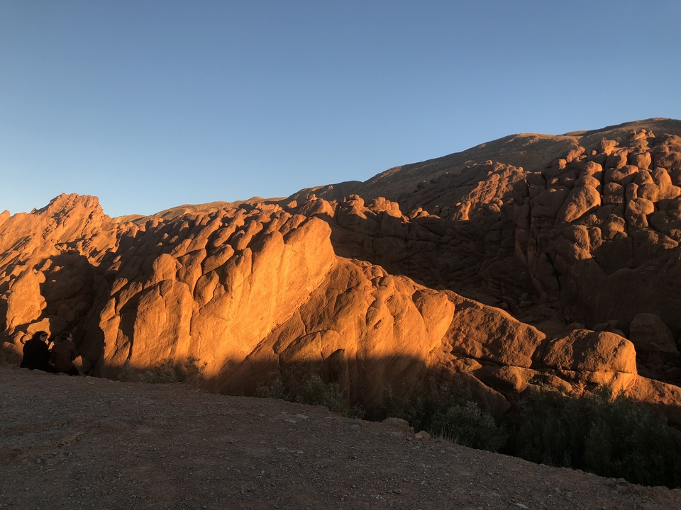 Two people enjoying a scenic view of rocky mountains during sunset.